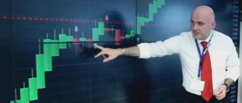 Renato Decarolis indica un grafico a candele Heikin Ashi su un grande schermo